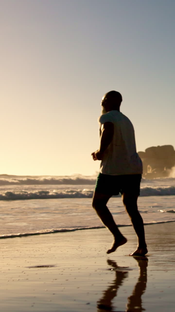 Coppia in silhouette che corre sulla spiaggia al tramonto dorato