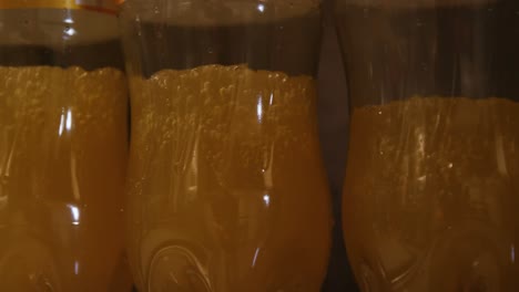 Close-up-bottles-being-filled-with-juice-on-production-line