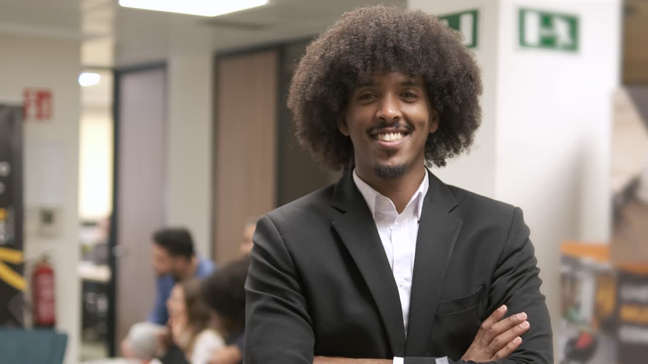 Happy confident creative businessman standing with arms crossed in office