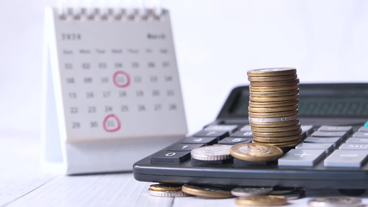 monedas apiladas en una calculadora con calendario