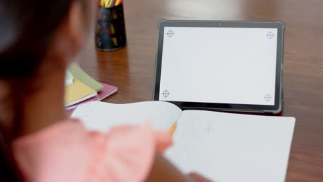 chica biracial teniendo clase de escuela primaria en la tableta con espacio de copia en la pantalla, cámara lenta