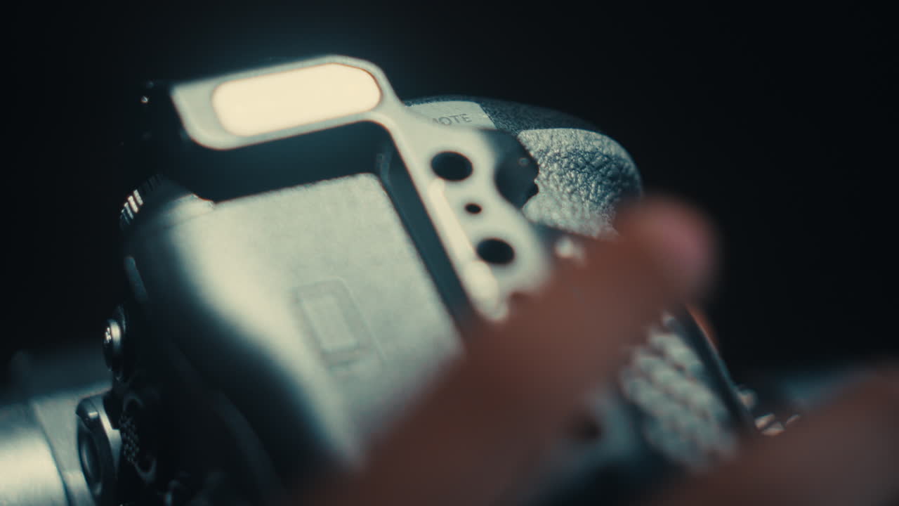 Macro footage of a professional photographer's hand inserting a battery into a digital camera slot