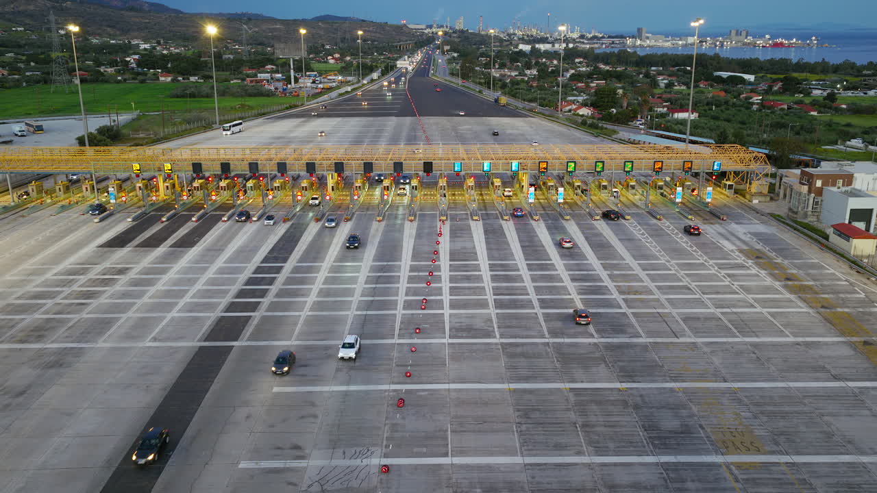 Plaza de peaje en autopista al anochecer con flujo de tráfico y carriles iluminados, infraestructura de transporte moderna.
