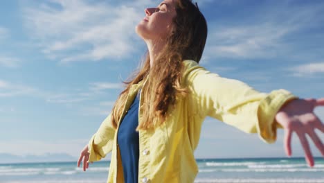 Caucasian-woman-with-arms-wide-at-the-beach-on-sunny-day