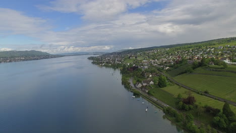 Drone-shot-flying-over-Lake-Zurich-towards-the-city-and-slowly-descending-down-towards-the-shore