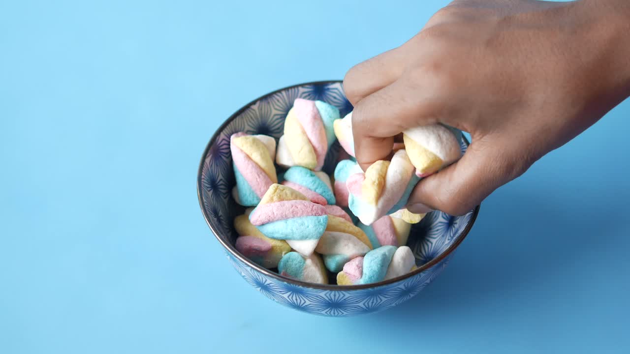 Mano che prende marshmallow colorati da una ciotola