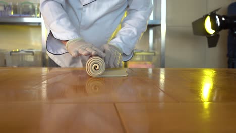 french pastry chef spreading croissant dough on the table, slow motion