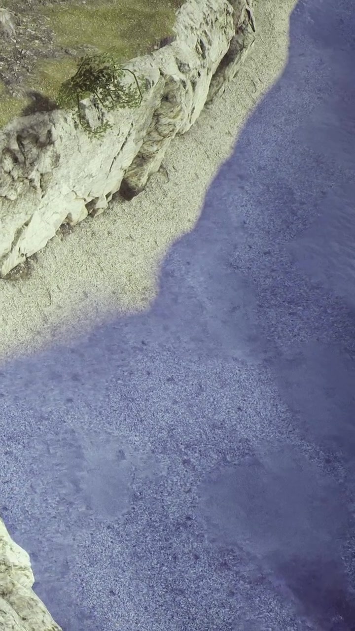 Acque azzurre incontrano una costa rocciosa in un ambiente naturale con vegetazione circostante.
