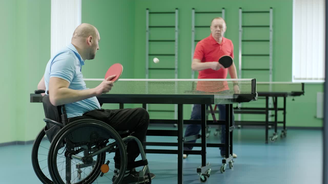 un hombre en silla de ruedas juega al ping-pong. personas con discapacidad juegan al tenis de mesa. rehabilitación de discapacitados. deporte.