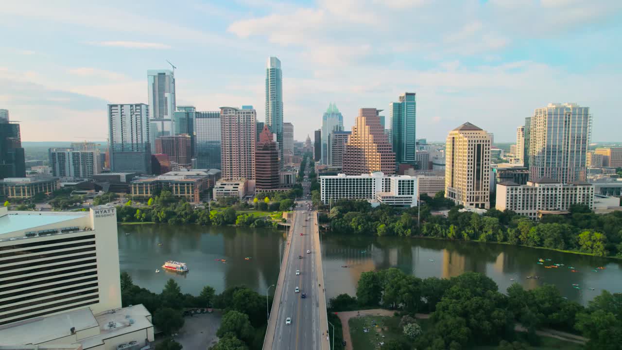 tomada aérea de drones del icónico puente de la avenida del congreso de austin y el capitolio del estado de texas con vistas al centro de la ciudad en el río colorado al atardecer, con coches, motociclistas y paddleboarders en el río