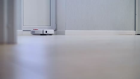 an automatic wireless robotic cleaner works in a white room.