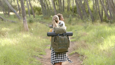 Young-Caucasian-woman-and-young-biracial-woman-hike-through-a-wooded-area