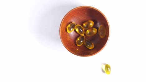 wooden bowl of yellow fish oil capsules