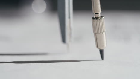close-up of a compass drawing a circle on paper