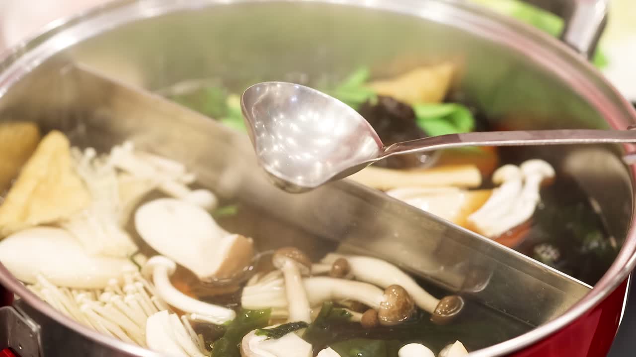 A ladle scoops vibrant vegetables and mushrooms from a steaming hotpot, highlighting fresh culinary preparation.