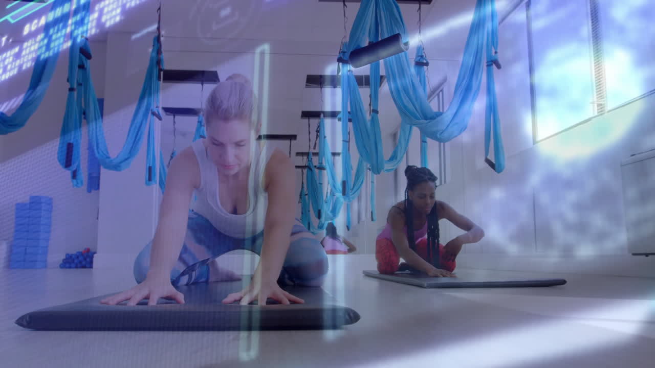Two women practicing fitness aerial yoga under hanging silks, featuring animated heart rate graph
