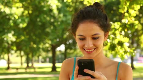 una hermosa morena enviando un texto en el parque