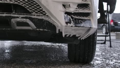 soap suds dripping from car's front bumper at carwash