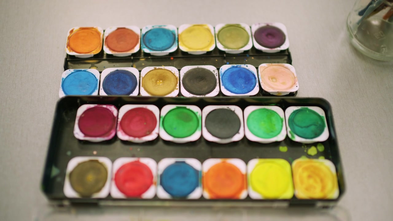 Close up of a watercolor palette with vibrant colors arranged in rows