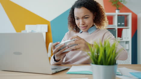 young woman playing mobile game in office