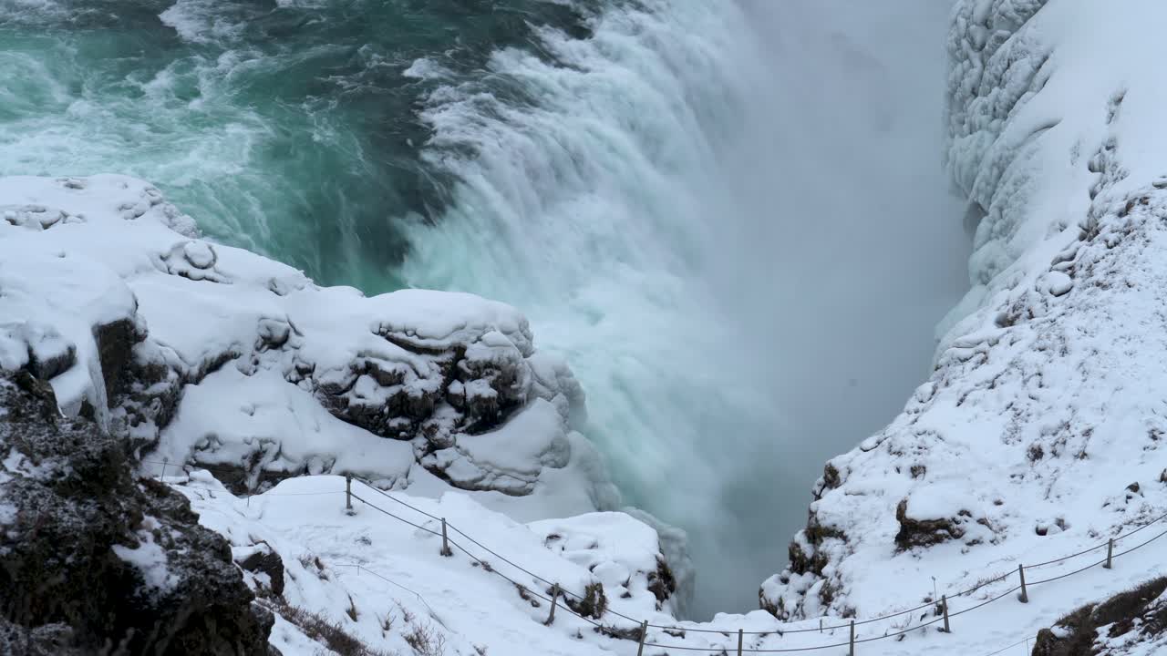toma aérea de arriba hacia abajo del agua que cae al valle durante el día de nieve - cascada de gullfoss en