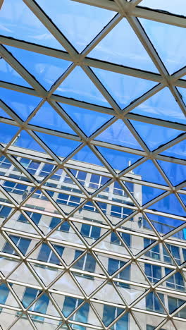 glass ceiling structure in urban setting. a modern glass ceiling features intricate geometry against a clear blue sky, showcasing architectural beauty