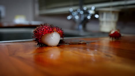 Lizard-walks-crawling-to-peeled-rambutan-eating-fruit-in-kitchen