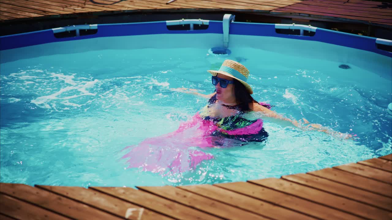Woman relaxing in a swimming pool with colorful float and sun hat enjoying a sunny day