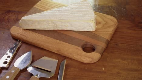 Two-blocks,-wedges-of-cheese-are-placed-onto-wooden-cutting-board