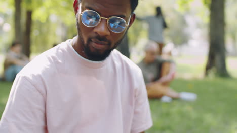 young black student typing on laptop in park