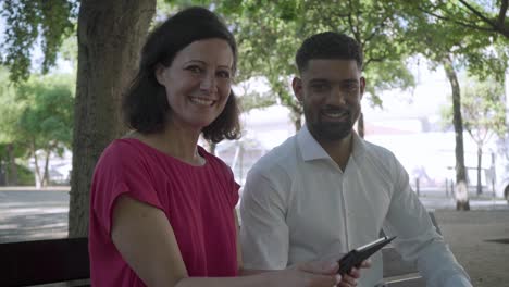 Fröhliches-Paar-Sitzt-Auf-Einer-Holzbank-Mit-Tablet.