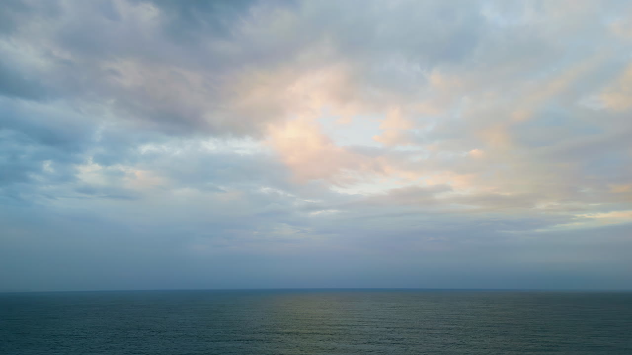 Dramatic sky dark ocean at twilight. Aerial rays breaking clouds over sea water.