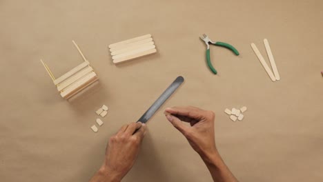 making handicrafts from popsicle sticks with nail file and pliers