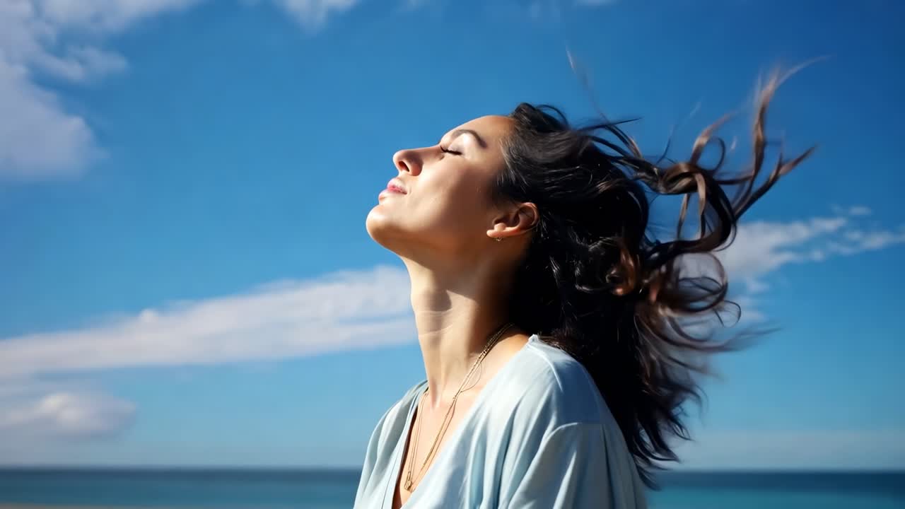 A serene video captures a woman in profile, eyes closed, hair flowing, against a bright blue sky