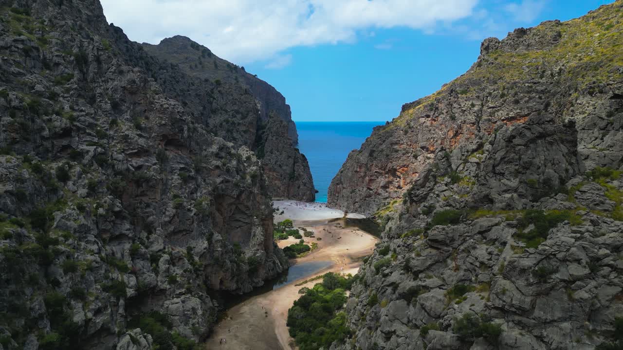 La cala e la spiaggia di Sa Calobra, incastonate tra le imponenti scogliere rocciose nella catena montuosa della Serra de Tramuntana. Il canyon del Torrent de Pareis incontra qui l'acqua turchese cristallina.