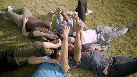 Smiling-young-guys-holding-smartphones-in-outstretched-arms.