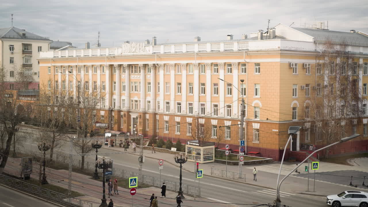 화려한 노란색 건물, 움직이는 자동차, 구름이 많은 날 교통 표지판, 거리 조명 및 대중교통을 특징으로하는 바쁜 도시 교차로의 가까운 시각