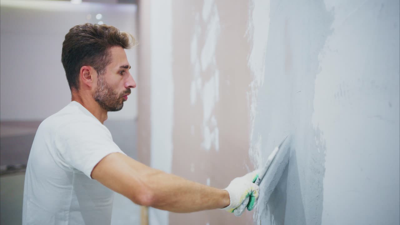 A Dedicated Painter Skillfully Applies Finishing Touches to a Wall, Showcasing Precision and Craftsmanship in Interior Renovation Efforts for a Contemporary Space