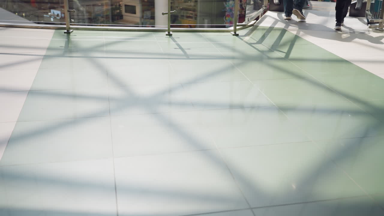 청바지와 검은색 부츠를 입고 는 사람을 포함하여 사람들의 발이 움직이는 쇼핑몰 타일 바닥의 전망.이 비디오는 활기찬 쇼핑 환경의 움직임과 역학을 강조합니다.