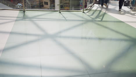 a view of a mall tile floor with people's feet moving, including a person wearing jeans and black boots walking. this video emphasizes the movement and dynamics of a bustling shopping environment