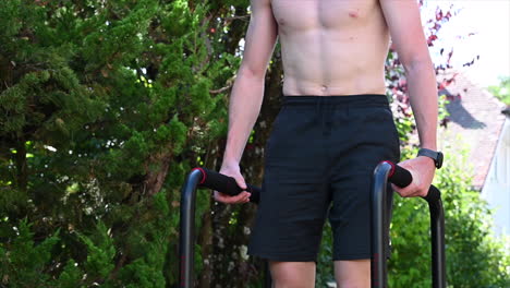 un joven atleta está haciendo su entrenamiento de calistenia con barras paralelas en su jardín, después del descanso, el próximo set