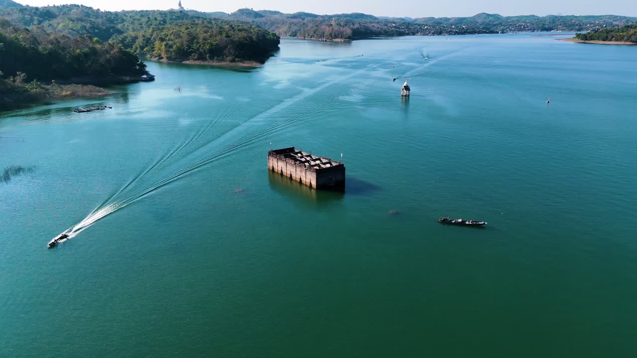 Wooden boats go around an underwater temple that is in the center of a beautiful blue lake that was once a thriving village