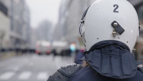 female police officer against blue flashing lights in the background during riots - pov shot over shoulder