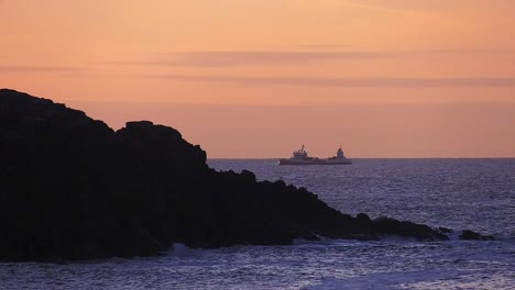 Sonnenuntergangsaufnahme-Eines-Fischereifahrzeugs,-Das-über-Eine-Landzunge-An-Einer-Klippe-Hinausfährt