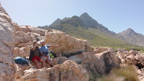 Happy-senior-biracial-couple-in-mountains-resting-at-sea,-in-slow-motion