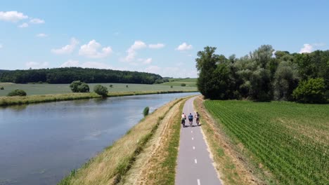 group of people cycling on a trail next to a river morava, czech republic 4k