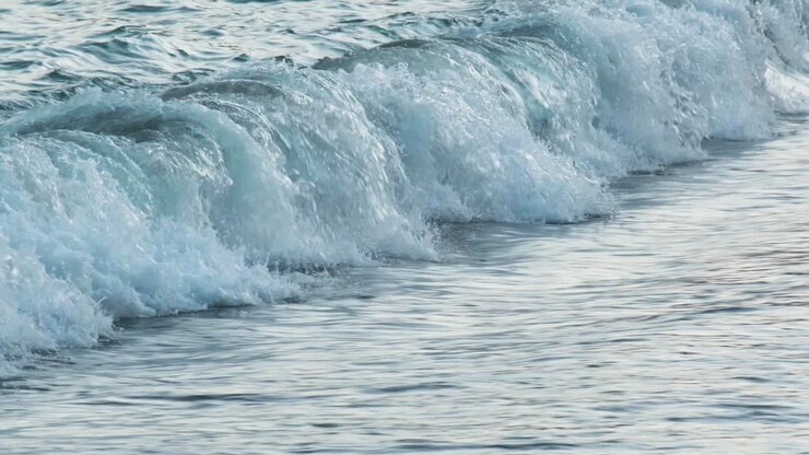 Zeitlupe von wunderschönen blauen Meerwasserwellen, die an einen tropischen Sandstrand schlagen.