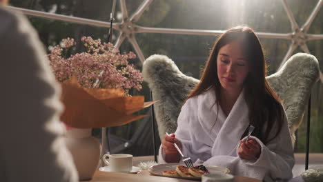 girl enjoying breakfast in a modern glass dome