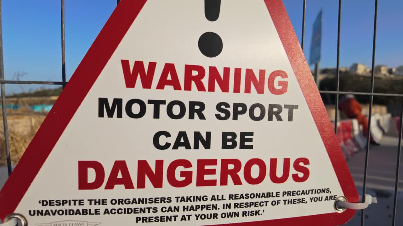 Sow motion camera reveal captures warning sign at the Malta Classic 2025 stating "Warning: Motor sport can be dangerous" and cautioning about racing risks despite all reasonable safety precautions