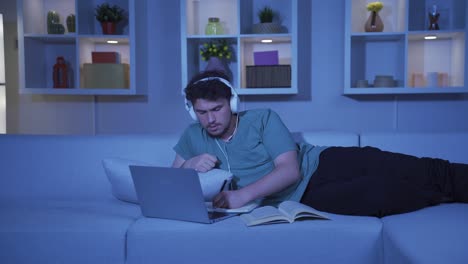 male student listening to music and studying at night.